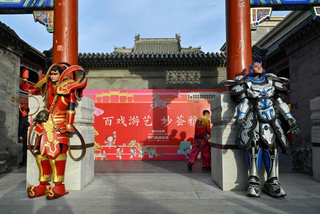 Men dressed in guardian outfits stand at a gate in Beijing on February 14, 2026, ahead of the Lunar New Year of the Horse. (Photo by ADEK BERRY / AFP)