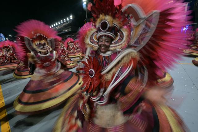 This slow shutter speed photography shows revellers of the Dragoes da Real samba school performing during the carnival parade at the Anhembi Sambadrome in Sao Paulo, Brazil, on February 14, 2026. (Photo by NELSON ALMEIDA / AFP)