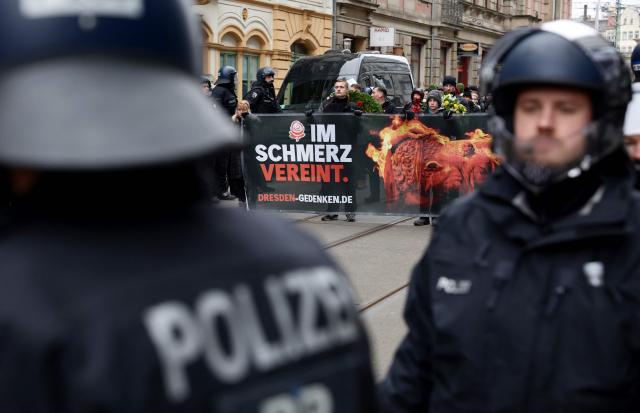 Policemen stand in front of right-wing extremists holding a banner that reads "United in Pain" as they march through the streets of Dresden, eastern Germany, on February 14, 2026. Right-wing extremists have organised a demonstration on the occasion of the 81st anniversary of the bombing of Dresden during WWII, as the a action alliance "Dresden Wi(e)dersetzen" was calling for a countermarch. (Photo by Jens Schlueter / AFP)