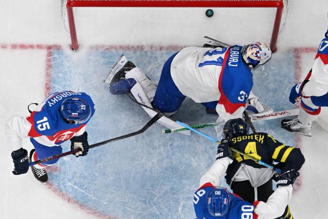 TOPSHOT - Sweden's #14 Joel Eriksson Ek (2R) scores his team's first goal against Slovakia's #31 Samuel Hlavaj during the men's preliminary round Group B Ice Hockey match between Sweden and Slovakia at the Milano Santagiulia Ice Hockey Arena during the Milano Cortina 2026 Winter Olympic Games in Milan, on February 14, 2026. (Photo by JULIEN DE ROSA / AFP)