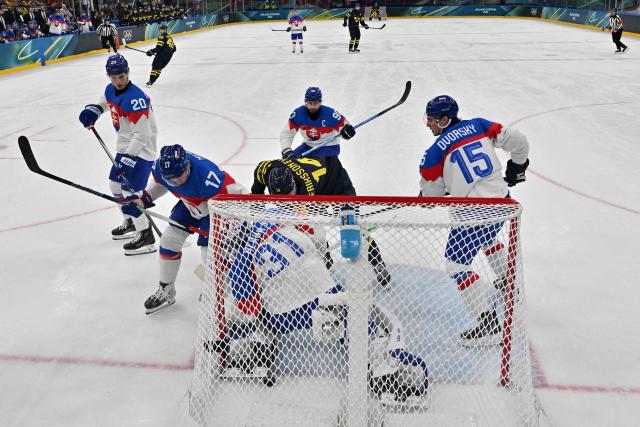 Sweden's #14 Joel Eriksson Ek (C) scores his team's first goal during the men's preliminary round Group B Ice Hockey match between Sweden and Slovakia at the Milano Santagiulia Ice Hockey Arena during the Milano Cortina 2026 Winter Olympic Games in Milan, on February 14, 2026. (Photo by JULIEN DE ROSA / POOL / AFP)