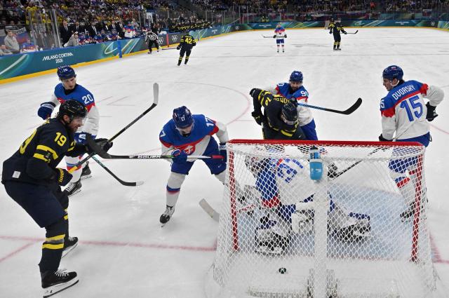 Sweden's #14 Joel Eriksson Ek (3R) scores his team's first goal during the men's preliminary round Group B Ice Hockey match between Sweden and Slovakia at the Milano Santagiulia Ice Hockey Arena during the Milano Cortina 2026 Winter Olympic Games in Milan, on February 14, 2026. (Photo by JULIEN DE ROSA / POOL / AFP)