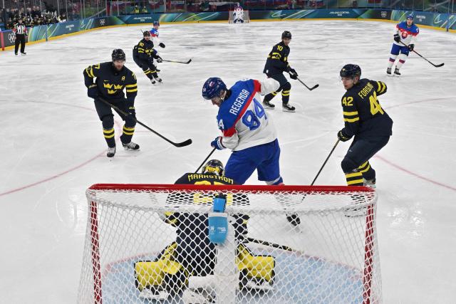 Slovakia's #84 Pavol Regenda and Sweden's #25 Jacob Markstrom vie for the puck during the men's preliminary round Group B Ice Hockey match between Sweden and Slovakia at the Milano Santagiulia Ice Hockey Arena during the Milano Cortina 2026 Winter Olympic Games in Milan, on February 14, 2026. (Photo by JULIEN DE ROSA / POOL / AFP)