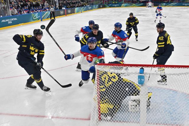 Slovakia's #11 Milos Kelemen and Sweden's #26 Rasmus Dahlin (L) vie for the puck during the men's preliminary round Group B Ice Hockey match between Sweden and Slovakia at the Milano Santagiulia Ice Hockey Arena during the Milano Cortina 2026 Winter Olympic Games in Milan, on February 14, 2026. (Photo by JULIEN DE ROSA / POOL / AFP)