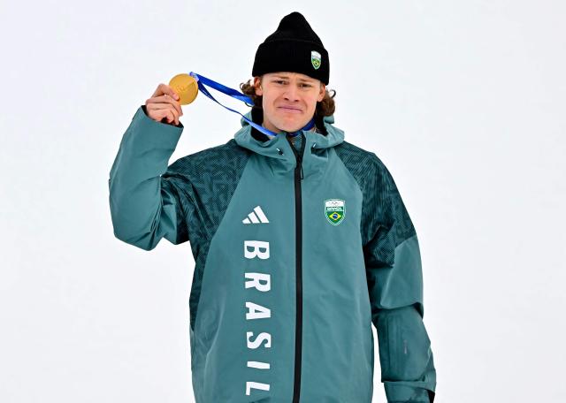 Brazil's gold medalist Lucas Pinheiro Braathen holds up his medal on the podium of the men's giant slalom alpine skiing event during the Milano Cortina 2026 Winter Olympic Games at the Stelvio Ski Centre in Bormio (Valtellina) on February 14, 2026. (Photo by Fabrice COFFRINI / AFP)