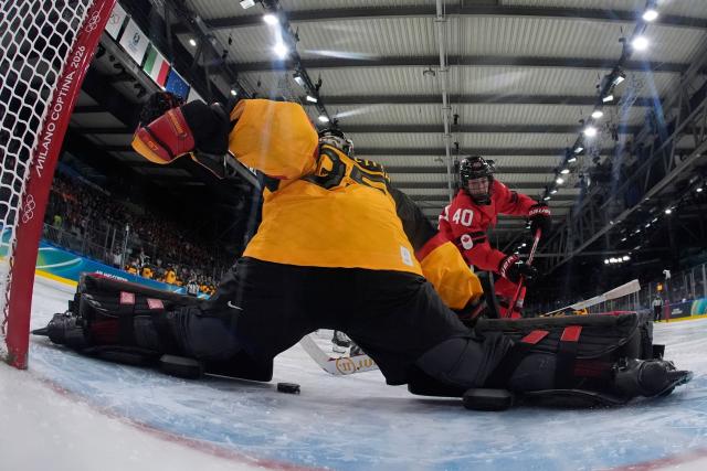 Canada's forward #40 Blayre Turnbull hits the puck between Germany's #35 Sandra Abstreiter's knees to scores her team's fourth goal during the women's quarter final ice hockey match between Canada and Germany at the Milano Rho Ice Hockey Arena at the Milano Cortina 2026 Winter Olympic Games in Milan, on February 14, 2026. (Photo by Darko Bandic / POOL / AFP)