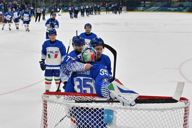 Team mates react with Italy's #35 Davide Fadani after the men's preliminary round Group B Ice Hockey match between Finland and Italy at the Milano Santagiulia Ice Hockey Arena during the Milano Cortina 2026 Winter Olympic Games in Milan, on February 14, 2026. Finland won the match 11-0. (Photo by JULIEN DE ROSA / POOL / AFP)