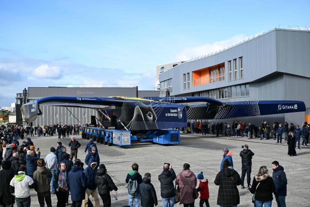Members of the crowd watch as the new Gitana 18 Edmond de Rothschild multihull is moved ahead of it’s launch, in Lorient, western France, on February 14, 2026. (Photo by Sebastien Salom-Gomis / AFP)