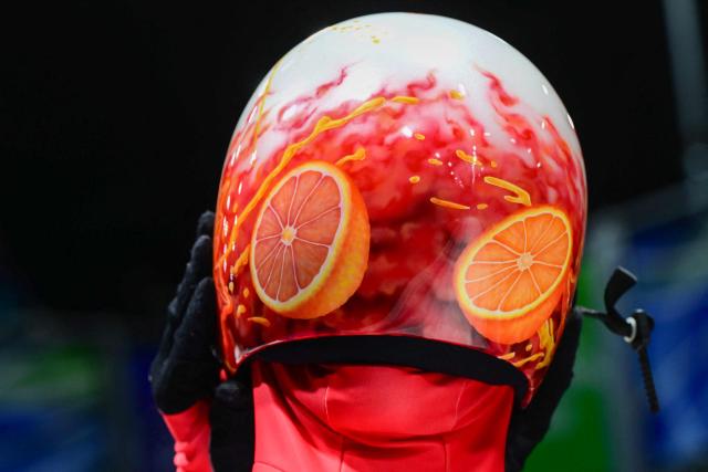 Canada's Hallie Clarke takes off her helmet in the finish area after competing in the skeleton women's heat 4 at Cortina Sliding Centre during the Milano Cortina 2026 Winter Olympic Games in Cortina d'Ampezzo on February 14, 2026. (Photo by Stefano RELLANDINI / AFP)