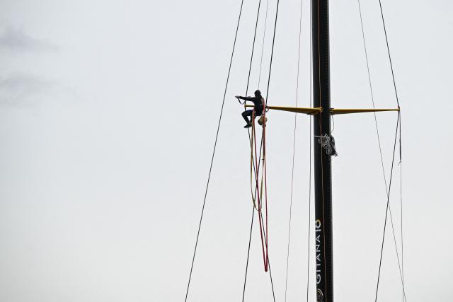 Gitana team member climbs the mast of the new multihull Gitana 18 Edmond de Rothschild after its inaugration on February 14, 2026, in Lorient, western France. (Photo by Sebastien Salom-Gomis / AFP)