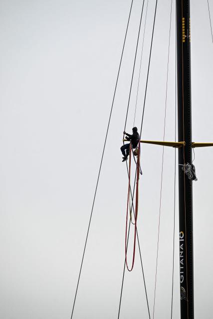 Gitana team member climbs the mast of the new multihull Gitana 18 Edmond de Rothschild after its inaugration on February 14, 2026, in Lorient, western France. (Photo by Sebastien Salom-Gomis / AFP)
