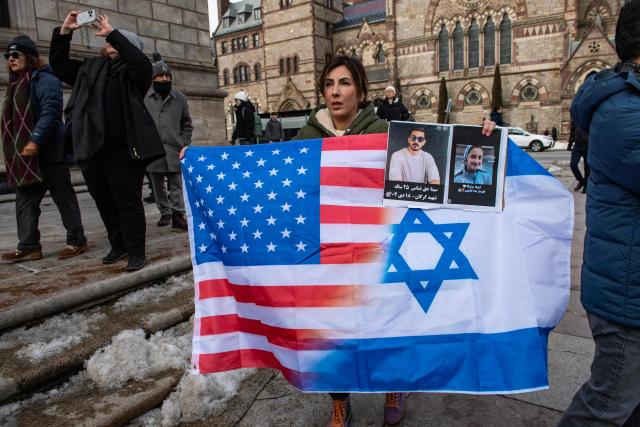 A demonstrator holds a combined US and Israeli flag as protestors called for regime change in Iran, US intervention and for the end of the Islamic Republic at a rally in Copley Square in Boston, Massachusetts, on February 14, 2026. The protest comes after the bloody crackdown on protesters last month, while US President Donald Trump has been massing warships in the Middle East and declared Friday that a change of government in Iran would be the "best thing that could happen". (Photo by Joseph Prezioso / AFP)