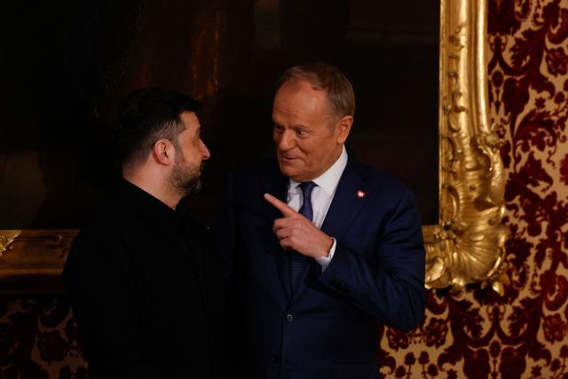 Polish Prime Minister Donald Tusk (R) and Ukrainian President Volodymyr Zelensky react prior to the traditional dinner on the occasion of the Munich Security Conference (MSC), on February 14, 2026 at the Munich Residence palace in Munich, southern Germany. (Photo by Michaela STACHE / AFP)