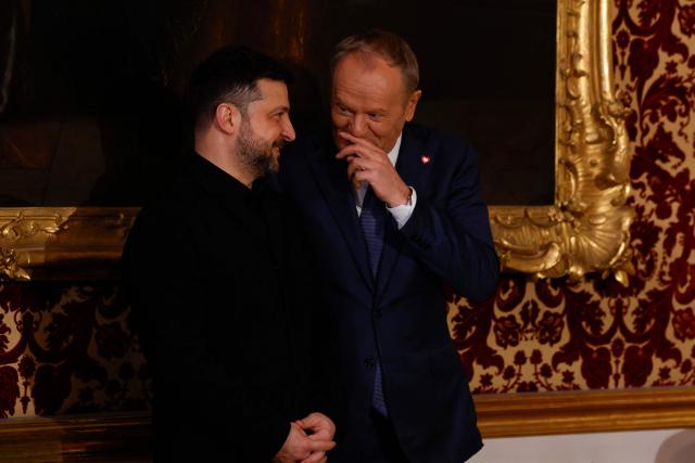 Polish Prime Minister Donald Tusk and Ukrainian President Volodymyr Zelensky react prior to the traditional dinner on the occasion of the Munich Security Conference (MSC), on February 14, 2026 at the Munich Residence palace in Munich, southern Germany. (Photo by Michaela STACHE / AFP)