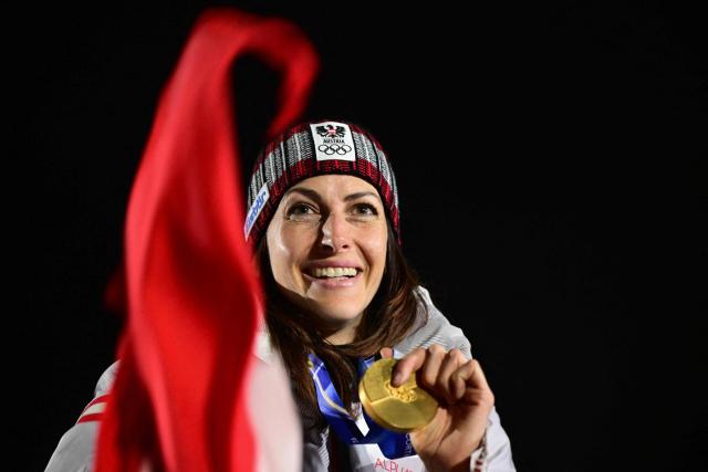 Austria's gold medalist Janine Flock holds up her medal on the podium after competing in the skeleton women's event at Cortina Sliding Centre during the Milano Cortina 2026 Winter Olympic Games in Cortina d'Ampezzo on February 14, 2026. (Photo by Stefano RELLANDINI / AFP)