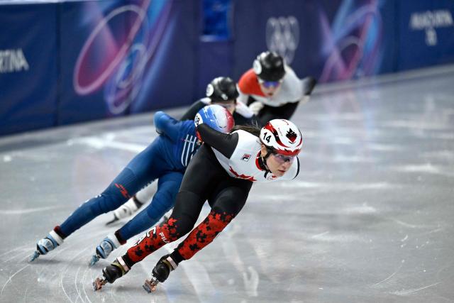 Canada's Courtney Sarault (front), France's Cloe Ollivier and Hungary's Diana Laura Vegi compete in the short track speed skating women's 1000m heats during the Milano Cortina 2026 Winter Olympic Games at Milano Ice Skating Arena in Milan on February 14, 2026. (Photo by WANG Zhao / AFP)