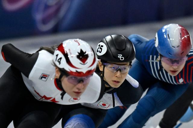 Japan's Ami Hirai (C), Canada's Courtney Sarault (L) and France's Cloe Ollivier compete in the short track speed skating women's 1000m heats during the Milano Cortina 2026 Winter Olympic Games at Milano Ice Skating Arena in Milan on February 14, 2026. (Photo by WANG Zhao / AFP)