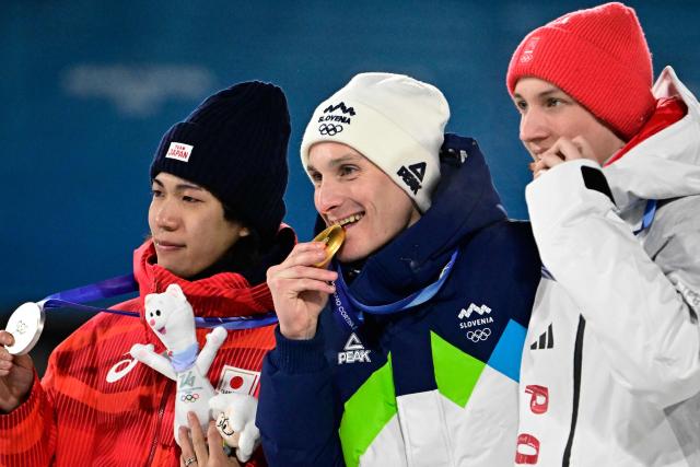 (From L) Silver medallist Japan's Ren Nikaido, gold medallist Slovenia's Domen Prevc and bronze medallist Poland's Kacper Tomasiak celebrate on the podium of the men's large hill individual ski jumping of the Milano Cortina 2026 Winter Olympic Games at Predazzo Ski Jumping Stadium in Predazzo (Val di Fiemme), on February 14, 2026. (Photo by Tobias SCHWARZ / AFP)