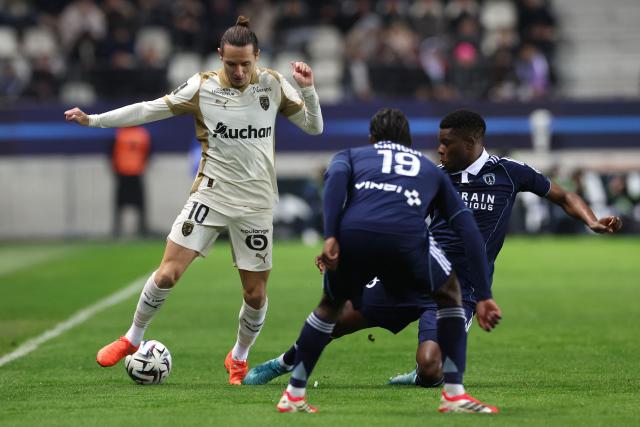 Lens' French forward #10 Florian Thauvin (L) fights for the ball with Paris FC's French defender #19 Nhoa Sangui (C) and Paris FC's Zimbabwean midfielder #18 Marshall Munetsi (R) during the French L1 football match between Paris FC and RC Lens at the Stade Jean-Bouin in Paris on February 14, 2026. (Photo by ALAIN JOCARD / AFP)