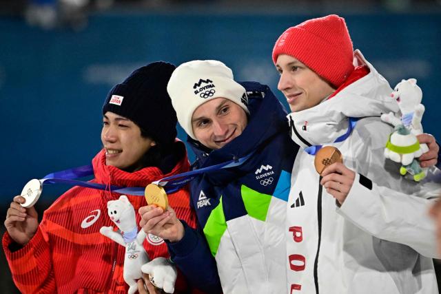 (From L) Silver medallist Japan's Ren Nikaido, gold medallist Slovenia's Domen Prevc and bronze medallist Poland's Kacper Tomasiak celebrate on the podium of the men's large hill individual ski jumping of the Milano Cortina 2026 Winter Olympic Games at Predazzo Ski Jumping Stadium in Predazzo (Val di Fiemme), on February 14, 2026. (Photo by Tobias SCHWARZ / AFP)