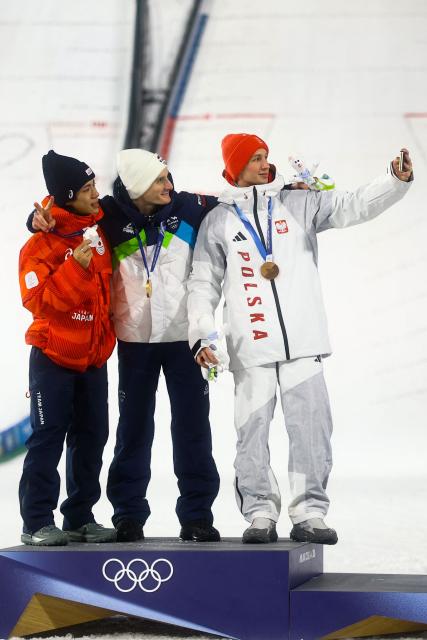 (From L) Silver medallist Japan's Ren Nikaido, gold medallist Slovenia's Domen Prevc and bronze medallist Poland's Kacper Tomasiak celebrate on the podium of the men's large hill individual ski jumping of the Milano Cortina 2026 Winter Olympic Games at Predazzo Ski Jumping Stadium in Predazzo (Val di Fiemme), on February 14, 2026. (Photo by Anne-Christine POUJOULAT / AFP)