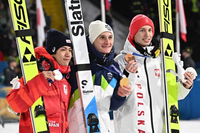 (From L) Silver medallist Japan's Ren Nikaido, gold medallist Slovenia's Domen Prevc and bronze medallist Poland's Kacper Tomasiak celebrate on the podium of the men's large hill individual ski jumping of the Milano Cortina 2026 Winter Olympic Games at Predazzo Ski Jumping Stadium in Predazzo (Val di Fiemme), on February 14, 2026. (Photo by Javier SORIANO / AFP)