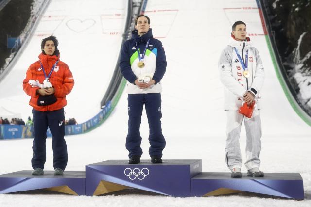 (From L) Silver medallist Japan's Ren Nikaido, gold medallist Slovenia's Domen Prevc and bronze medallist Poland's Kacper Tomasiak celebrate on the podium of the men's large hill individual ski jumping of the Milano Cortina 2026 Winter Olympic Games at Predazzo Ski Jumping Stadium in Predazzo (Val di Fiemme), on February 14, 2026. (Photo by Anne-Christine POUJOULAT / AFP)