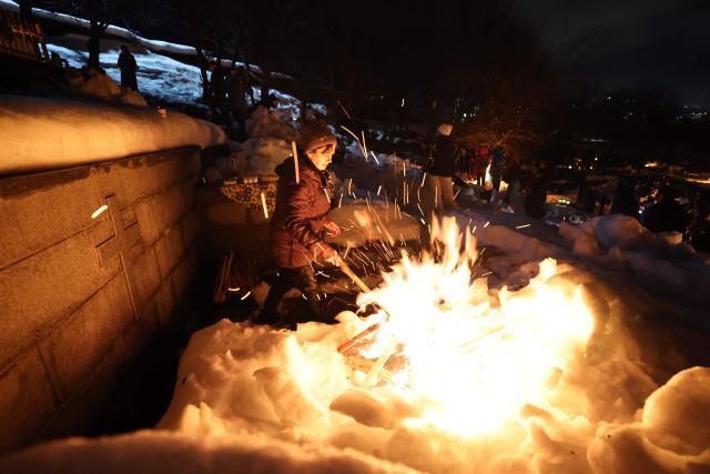 Georgians celebrate Lamproba, a traditional religious festival honouring the dead by burning fires at their graves, what is believed warming their souls, in the highland townlet of Mestia, located at an elevation of 1,500 metres (4,921 feet) in the Caucasus Mountains, in northwestern Georgia's Svaneti region on February 14, 2026. (Photo by Giorgi ARJEVANIDZE / AFP)