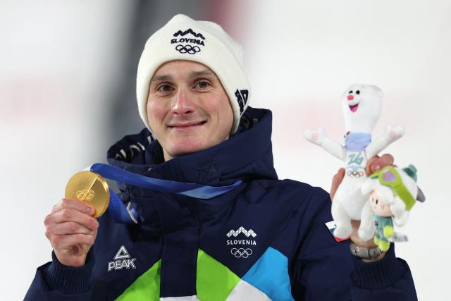 Gold medallist Slovenia's Domen Prevc celebrates on the podium of the men's large hill individual ski jumping of the Milano Cortina 2026 Winter Olympic Games at Predazzo Ski Jumping Stadium in Predazzo (Val di Fiemme), on February 14, 2026. (Photo by Anne-Christine POUJOULAT / AFP)