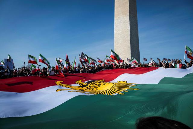 Demonstrators hold a large Iranian flag dating from before the 1979 Islamic revolution during a march in support of the people of Iran by members of the American-Iranian community in Washington, DC, on February 14, 2026. The demonstration comes after the bloody crackdown on protesters last month, while US President Donald Trump has been massing warships in the Middle East and declared Friday that a change of government in Iran would be the "best thing that could happen". (Photo by ROBERTO SCHMIDT / AFP)