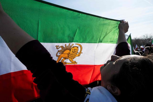 A demonstrator chants slogans while holding an Iranian flag dating from before the 1979 Islamic revolution during a march in support of the people of Iran by members of the American-Iranian community in Washington, DC, on February 14, 2026. The demonstration comes after the bloody crackdown on protesters last month, while US President Donald Trump has been massing warships in the Middle East and declared Friday that a change of government in Iran would be the "best thing that could happen". (Photo by ROBERTO SCHMIDT / AFP)