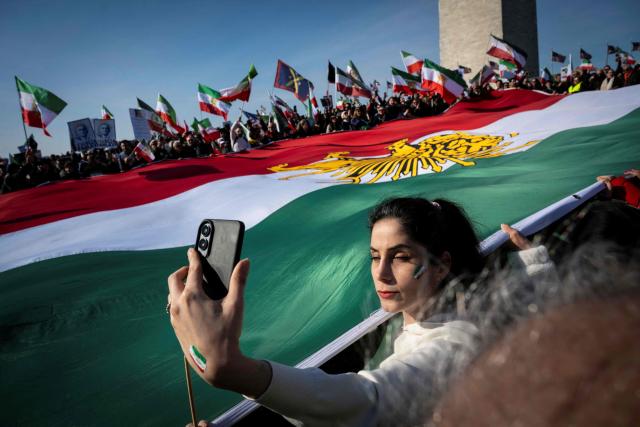 Demonstrators hold a large Iranian flag dating from before the 1979 Islamic revolution during a march in support of the people of Iran by members of the American-Iranian community in Washington, DC, on February 14, 2026. The demonstration comes after the bloody crackdown on protesters last month, while US President Donald Trump has been massing warships in the Middle East and declared Friday that a change of government in Iran would be the "best thing that could happen". (Photo by ROBERTO SCHMIDT / AFP)