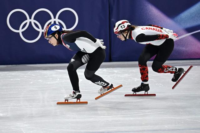 South Korea's Choi Min-jeong (L) and Canada's Kim Boutin compete in the short track speed skating women's 1000m heats during the Milano Cortina 2026 Winter Olympic Games at Milano Ice Skating Arena in Milan on February 14, 2026. (Photo by Gabriel BOUYS / AFP)