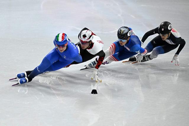 (L-R) Italy's Luca Spechenhauser, Canada's William Dandjinou, USA's Andrew Heo and Japan's Keita Watanabe compete in the short track speed skating men's 1500m semi-final during the Milano Cortina 2026 Winter Olympic Games at Milano Ice Skating Arena in Milan on February 14, 2026. (Photo by Gabriel BOUYS / AFP)