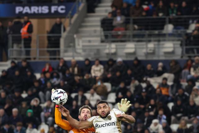 Paris FC's German goalkeeper #35 Kevin Trapp (CL) and Lens' French defender #14 Matthieu Udol (CR) fight for the ball in the air during the French L1 football match between Paris FC and RC Lens at the Stade Jean-Bouin in Paris on February 14, 2026. (Photo by Alain JOCARD / AFP)
