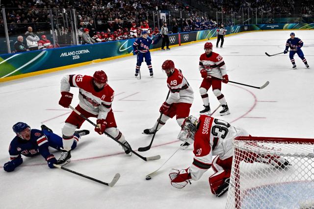 Denmark's #25 Oliver Lauridsen (2nd L) and Denmark's #30 Mads Sogaard vie for the puck with USA's #09 Jack Eichel (L) during the men's preliminary round Group C Ice Hockey match between USA and Denmark at the Milano Santagiulia Ice Hockey Arena during the Milano Cortina 2026 Winter Olympic Games in Milan, on February 14, 2026. (Photo by JULIEN DE ROSA / POOL / AFP)