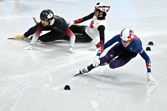 Canada's Felix Roussel (C) and Latvia's Roberts Kruzbergs (L) fall next to Britain's Niall Treacy while competing in the short track speed skating men's 1500m semi-final during the Milano Cortina 2026 Winter Olympic Games at Milano Ice Skating Arena in Milan on February 14, 2026. (Photo by Gabriel BOUYS / AFP)