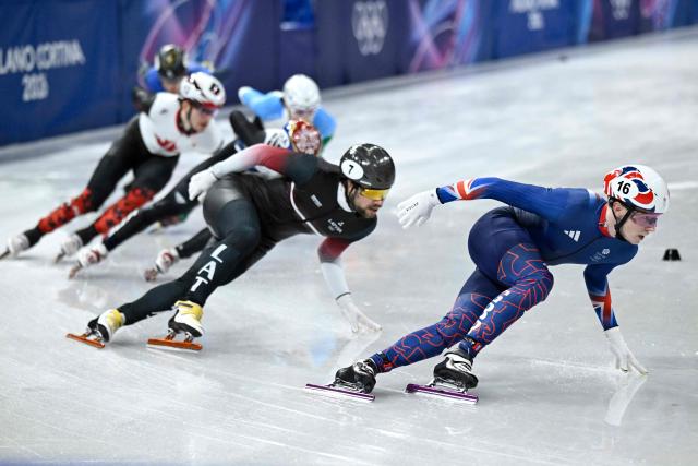 Britain's Niall Treacy leads past Latvia's Roberts Kruzbergs in the short track speed skating men's 1500m semi-final during the Milano Cortina 2026 Winter Olympic Games at Milano Ice Skating Arena in Milan on February 14, 2026. (Photo by WANG Zhao / AFP)