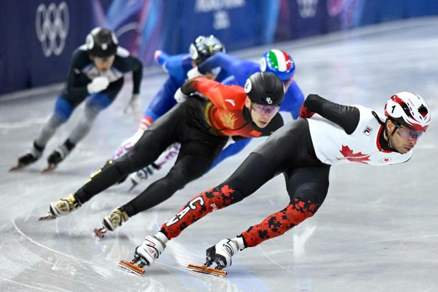 Canada's William Dandjinou (R) and China's Liu Shaoang compete in the short track speed skating men's 1500m semi-final during the Milano Cortina 2026 Winter Olympic Games at Milano Ice Skating Arena in Milan on February 14, 2026. (Photo by WANG Zhao / AFP)