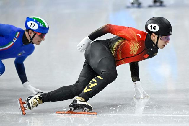 China's Liu Shaoang (R) and Italy's Luca Spechenhauser compete in the short track speed skating men's 1500m semi-final during the Milano Cortina 2026 Winter Olympic Games at Milano Ice Skating Arena in Milan on February 14, 2026. (Photo by WANG Zhao / AFP)