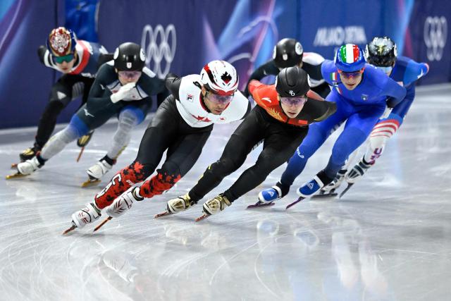 Canada's William Dandjinou (front), China's Liu Shaoang (3R) and Italy's Luca Spechenhauser compete in the short track speed skating men's 1500m semi-final during the Milano Cortina 2026 Winter Olympic Games at Milano Ice Skating Arena in Milan on February 14, 2026. (Photo by WANG Zhao / AFP)