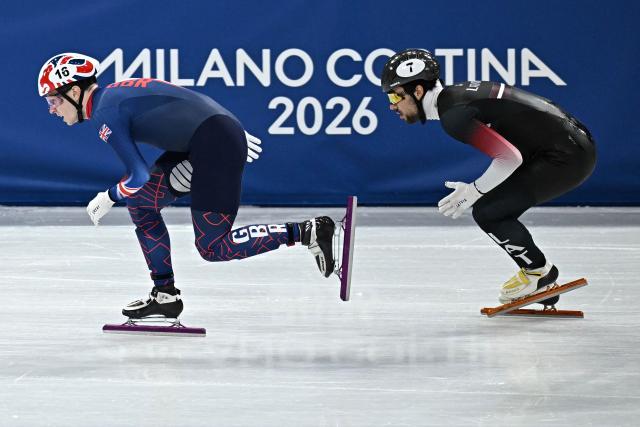 Britain's Niall Treacy (L) and Latvia's Roberts Kruzbergs compete in the short track speed skating men's 1500m semi-final during the Milano Cortina 2026 Winter Olympic Games at Milano Ice Skating Arena in Milan on February 14, 2026. (Photo by Gabriel BOUYS / AFP)