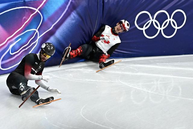 Canada's Felix Roussel (R) and Latvia's Roberts Kruzbergs fall while competing in the short track speed skating men's 1500m semi-final during the Milano Cortina 2026 Winter Olympic Games at Milano Ice Skating Arena in Milan on February 14, 2026. (Photo by Gabriel BOUYS / AFP)