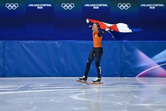 Netherlands' Jens van 't Wout celebrates with his country's flag after winning gold in the short track speed skating men's 1500m final during the Milano Cortina 2026 Winter Olympic Games at Milano Ice Skating Arena in Milan on February 14, 2026. (Photo by WANG Zhao / AFP)