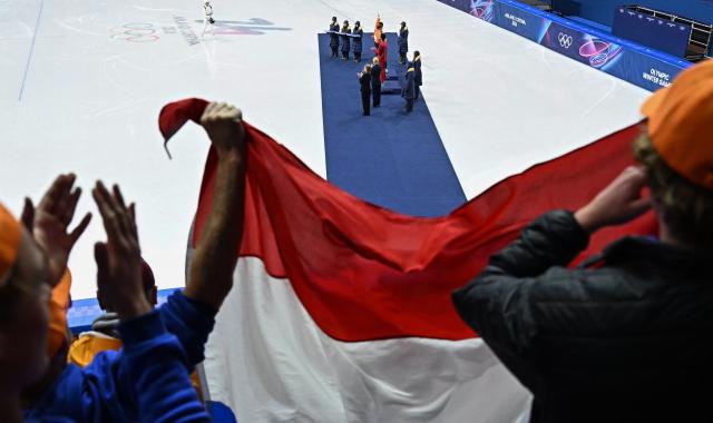 Fans hold Netherlands' flag while attending the victory ceremony of the short track speed skating men's 1500m final during the Milano Cortina 2026 Winter Olympic Games at Milano Ice Skating Arena in Milan on February 14, 2026. (Photo by Gabriel BOUYS / AFP)