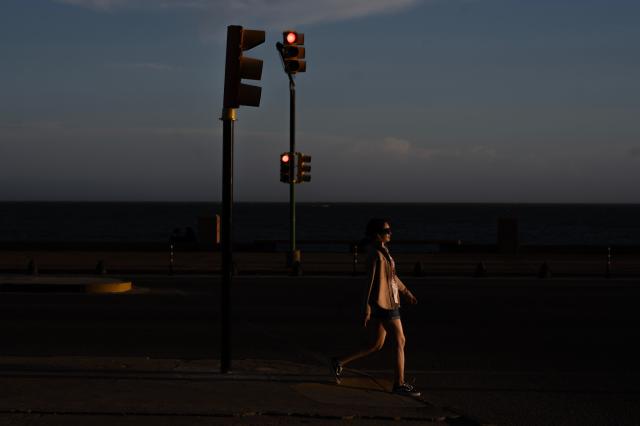 A woman crosses a street in front of Montevideo's Rambla on February 14, 2026. (Photo by Eitan ABRAMOVICH / AFP)