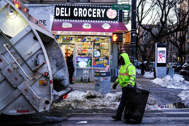 A Department of Sanitation employee empties a trash can into a garbage truck in New York,  on February 14, 2026. (Photo by Charly TRIBALLEAU / AFP)