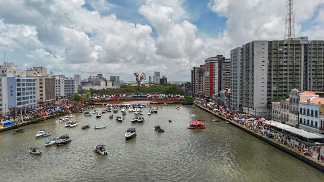 This aerial view shows revelers taking part in the Galo da Madrugada (Dawn Rooster) carnival band parade on the streets of Recife, Brazil on February 14, 2026. (Photo by Carlos FABAL / AFP)