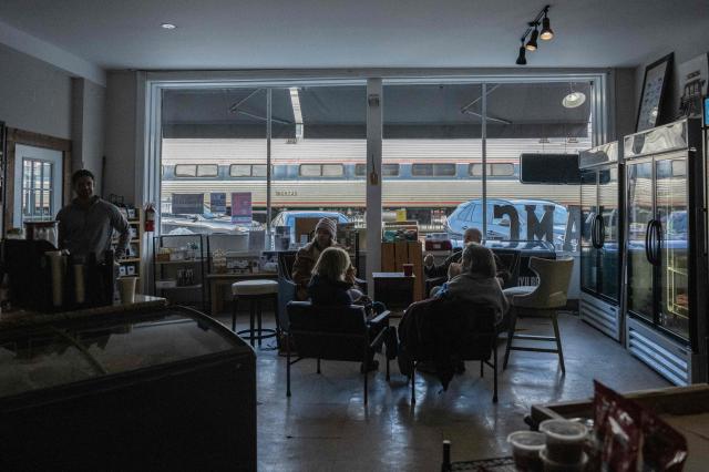 A group that gathers on a regular basis has coffee in a general store in Ashland, Virginia on February 12, 2026, as an Amtrak train passes in the background. In rural Virginia, dozens of young cows belonging to Chris Stem graze by a frozen pond. He is living his childhood dream of being a farmer -- but reality is starting to bite. Despite soaring beef prices as the US cattle population hit a 75-year low, farmers like Stem are feeling the squeeze from steeper business costs, budget-conscious consumers and President Donald Trump's trade policy. "The cost of doing business is almost outpricing (our ability) to continue to raise cattle," Stem told AFP. (Photo by ANDREW CABALLERO-REYNOLDS / AFP)