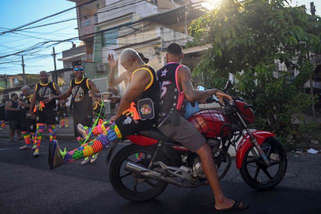 Revelers ride a motorbike before the parade of Dito e Feito bate-bola street carnival group at Iraja neighbourhood, in the suburbs of Rio de Janeiro, Brazil on February 14, 2026. (Photo by Mauro PIMENTEL / AFP)
